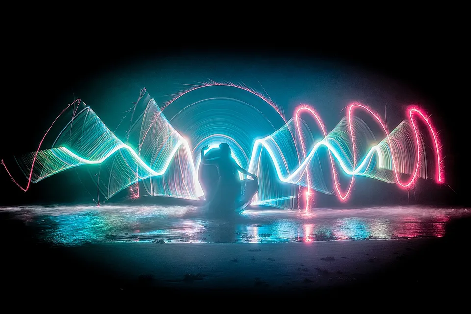 A silhouetted performer surrounded by sweeping cyan and pink light trails.