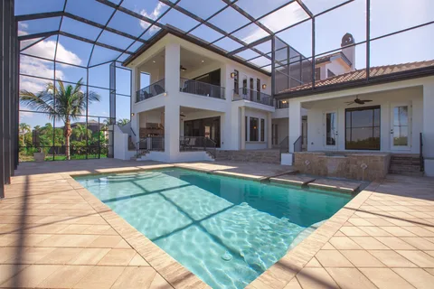A luxury waterfront home with a pool and screened patio
